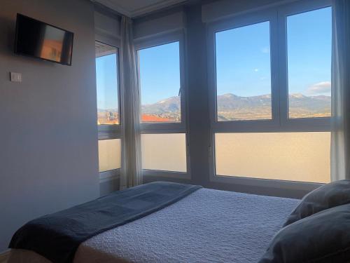 a bedroom with three windows and a bed with a view at Pensión San Vicente in San Vicente de la Sonsierra