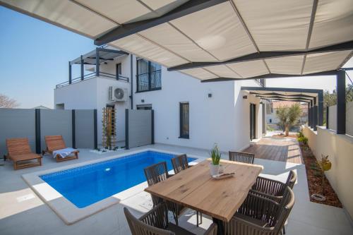 a patio with a wooden table and chairs and a swimming pool at Villa Magna luxury apartments in Murter