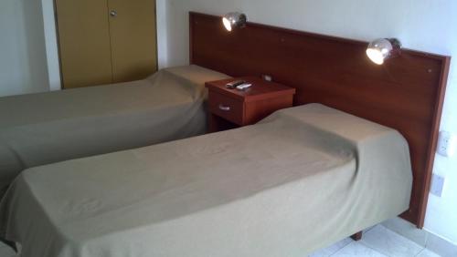 two beds in a hotel room with a nightstand and a bed sidx sidx sidx at Premier in Santiago del Estero