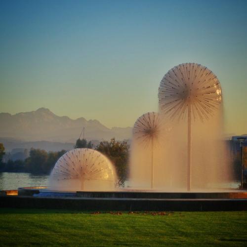 three large fountains in a field next to a lake at Lakelodge Romanshorn in Romanshorn