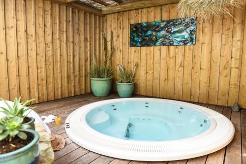 eine Whirlpool-Badewanne auf einer Terrasse mit Topfpflanzen in der Unterkunft The Originals Boutique La Villa Ouest & Spa in Saint-Palais-sur-Mer