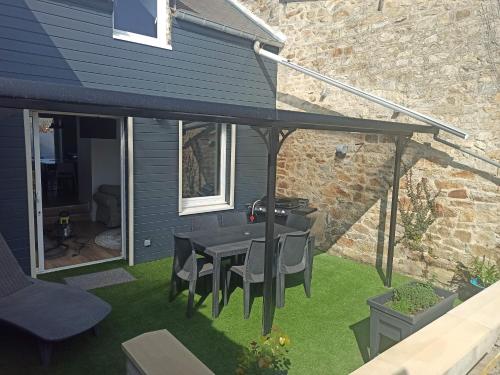 a patio with a table and chairs on the grass at "Mont 1er Pas" proche Mont St Michel in Pontorson