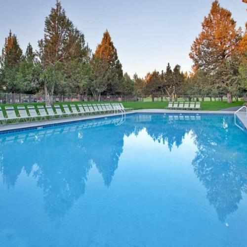 a large swimming pool with chairs and trees in a park at Juniper Ridge Chalet at Eagle Crest Resort in Redmond
