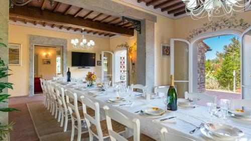 Villa Dimora San Jacopo في بالايا: غرفة طعام كبيرة مع طاولة طويلة مع كراسي بيضاء