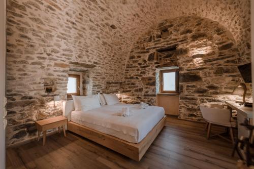 a bedroom with a bed in a stone wall at Alika Resort in Álika