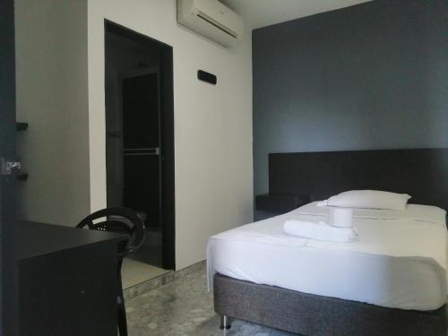 a bedroom with a white bed and a black door at Hotel Bucare in Yopal