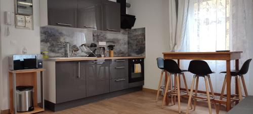 une cuisine avec des placards gris et des tabourets de bar dans l'établissement Résidence Romains 1G - hébergement de tourisme classé avec garage gratuit, à Strasbourg