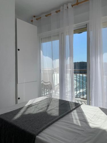 a white bedroom with a bed and a large window at Apartamento en primerísima línea de playa con espectaculares vistas Netflix, Prime y Disney in Oropesa del Mar