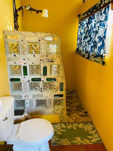 a bathroom with a toilet and a wall with tiles at Luminosa Uvita Hostel in Uvita