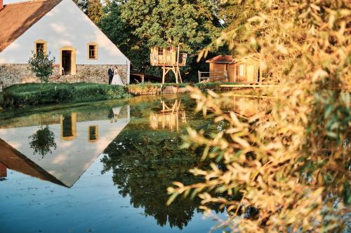 un riflesso di una sposa e di uno sposo nell'acqua al loro matrimonio di Strnadovský mlýn a Jesenice