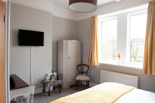 a bedroom with a refrigerator and a chair at Duchy House Bed and Breakfast in Princetown