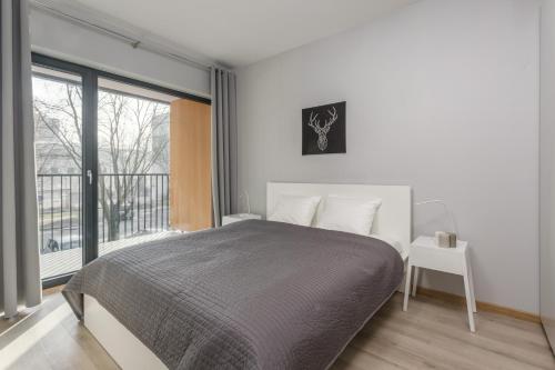 sypialnia z łóżkiem i dużym oknem w obiekcie Warsaw City Comfort Apartments w Warszawie