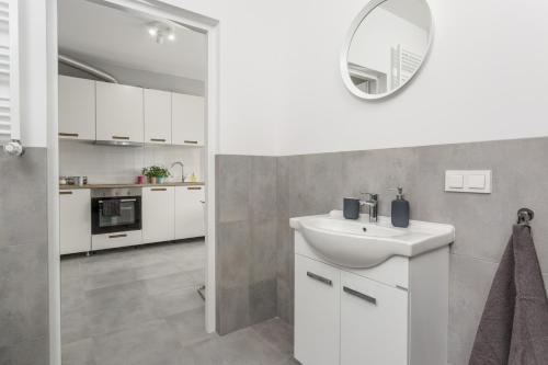 bagno bianco con lavandino e specchio di Warsaw City Comfort Apartments a Varsavia