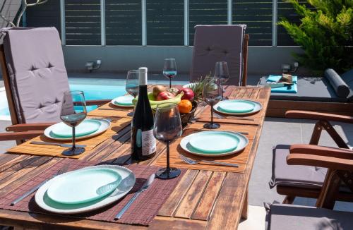 a wooden table with plates and wine glasses on it at Grey House "by Checkin" in Karteros
