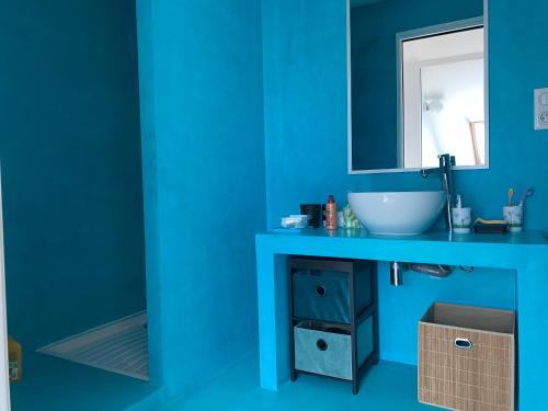 une salle de bain bleue avec un lavabo et un miroir dans l'établissement Duplex face mer tout confort sur la plage /tennis, à Pornichet