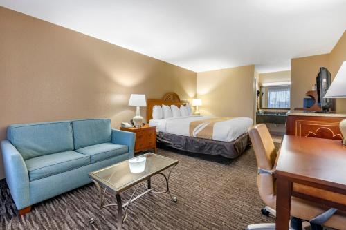 Habitación de hotel con cama y sofá azul en Quality Inn Kennedy Space Center, en Titusville