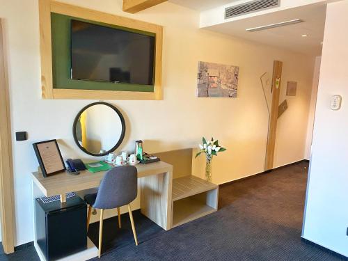 a room with a desk with a mirror and a tv at 16 Lakes Hotel in Grabovac