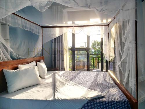a bedroom with a large bed with a large window at Hendo Hotel in Entebbe