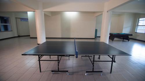 a ping pong table in the middle of a room with a pool table at Vasudev Heights Apartment near Yaya centre in Nairobi
