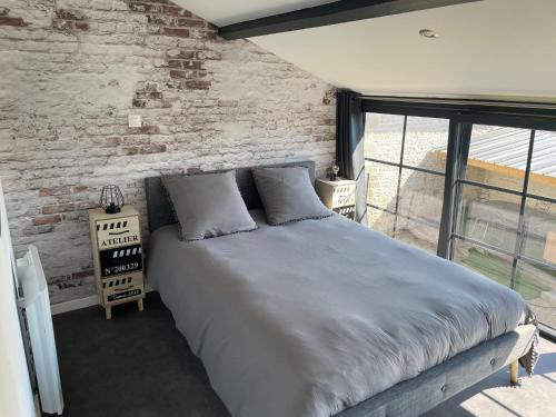 a bed in a room with a brick wall at Maison chaleureuse avec parking sur place in Saint-Gelais