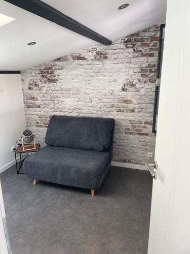 a couch in a room with a brick wall at Maison chaleureuse avec parking sur place in Saint-Gelais