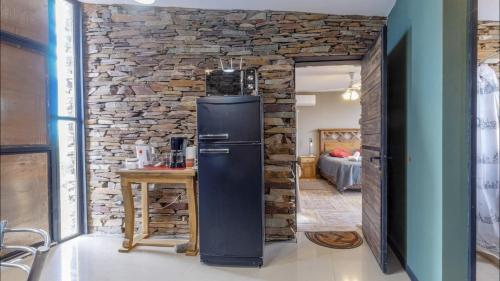 a refrigerator in a room with a stone wall at Las Crucesita wine lodge in Las Compuertas