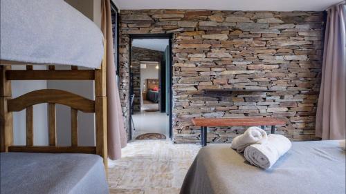 a bedroom with two beds and a stone wall at Las Crucesita wine lodge in Las Compuertas