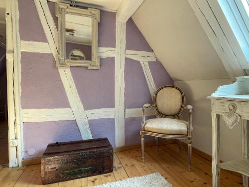 a room with a chair and a mirror on a wall at Gîte Aux P'tits Cœurs d'Alsace in Beblenheim
