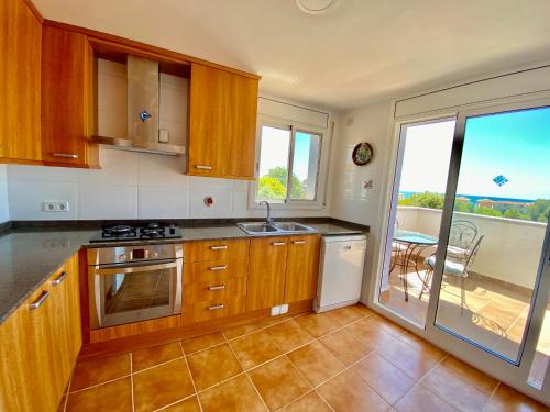 a kitchen with wooden cabinets and a view of a balcony at house on the beach in Calafell