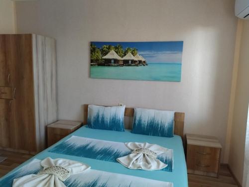 a bedroom with a bed with blue sheets and the ocean at Фамилна къща Джоко in Kiten
