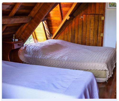 2 camas en una habitación con paredes de madera en Chalé com Piscina em Piranguçu - Serra Mantiqueira en Piranguçu