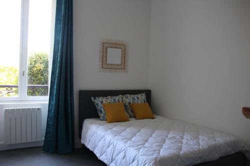 a bed with yellow pillows in a room with a window at Au fil de l'eau Studio Le P'tit Mousse in Lannion