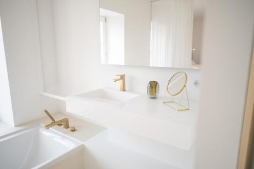 a white bathroom with a sink and a mirror at La Rose du Cèdre in Gray