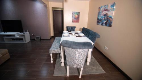 a room with a table and chairs and a television at Vasudev Heights Apartment near Yaya centre in Nairobi