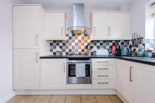 a kitchen with white cabinets and a stove top oven at Relaxing 3 Bedroom Chester Home with garden in Broughton