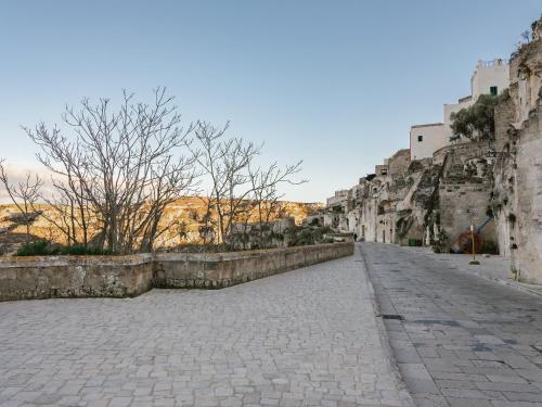 a cobblestone street with a stone wall and trees at San Giovanni Vecchio - Residenza in Matera