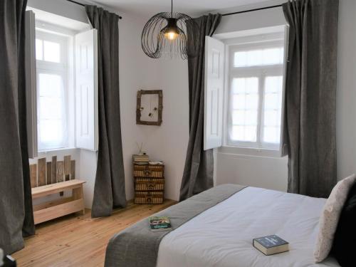 a bedroom with a bed and two windows at Casa da Livraria - Boutique da Cultura in Avis