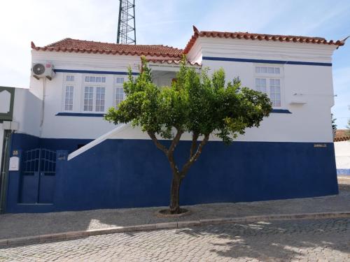 une maison bleue et blanche avec un arbre en face dans l'établissement Boutique da Cultura, à Aviz