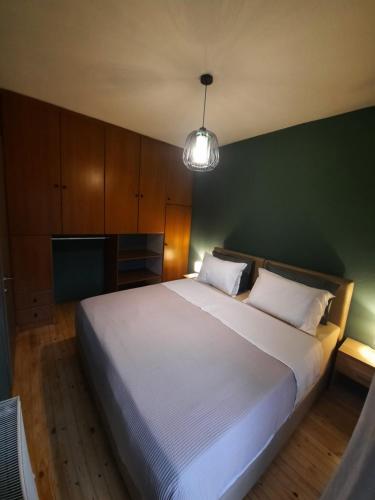 a bedroom with a large white bed with a green wall at Billie's guest house in Iraklitsa
