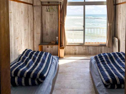 two beds in a room with a view of the ocean at MARINE-Q in Inami