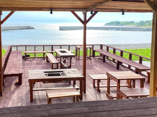 a wooden deck with picnic tables and benches on the beach at MARINE-Q in Inami