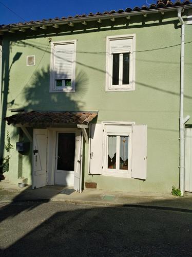 Casa verde con puertas y ventanas blancas en Repos au vert en Ariège, en Le Peyrat