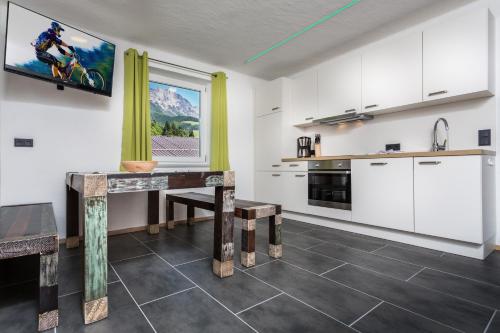 cocina con armarios blancos y mesa en Appartement Leogang, en Leogang