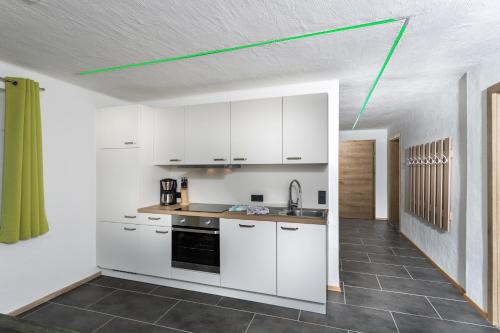 una cocina con armarios blancos y una línea verde en el techo en Appartement Leogang, en Leogang