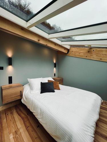um quarto com uma grande cama branca e uma clarabóia em LOFT sous un ciel étoilé 2/4 pers em Foix