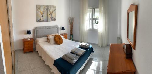 a bedroom with a bed and a table and a mirror at Apartamento con terraza en primera línea de playa in Conil de la Frontera
