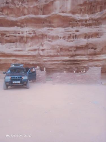 a jeep parked in front of a rock wall at golden day in Wadi Rum