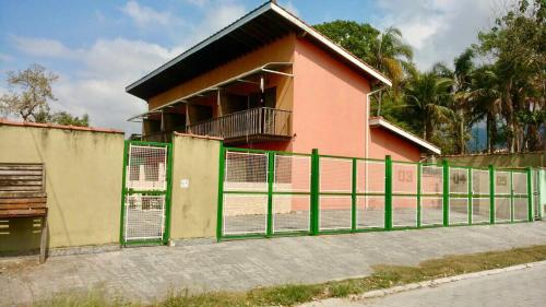 um edifício com uma cerca verde em frente em Massaguas beach em Caraguatatuba