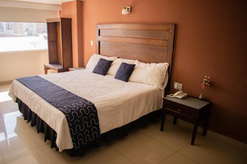 a bedroom with a large bed with blue pillows at Hotel Granda Inn in Tuxtla Gutiérrez