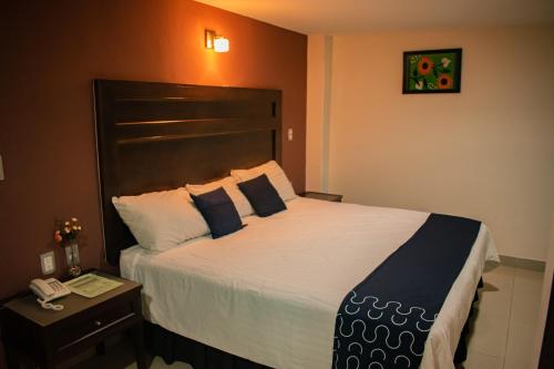 a bedroom with a large bed with a phone on a table at Hotel Granda Inn in Tuxtla Gutiérrez